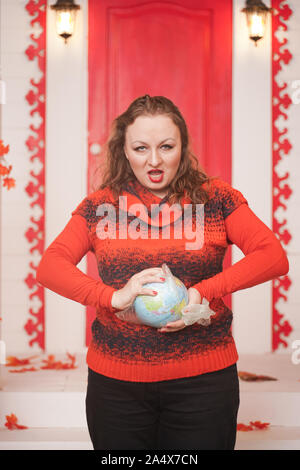 an emotional adult woman holds a planet in a plastic bag in her hands and shows irresponsible excessive consumer plastic. Stock Photo