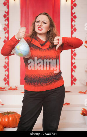 an emotional adult woman holds a planet in a plastic bag in her hands and shows irresponsible excessive consumer plastic. Stock Photo