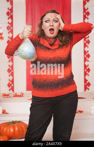 an emotional adult woman holds a planet in a plastic bag in her hands and shows irresponsible excessive consumer plastic. Stock Photo