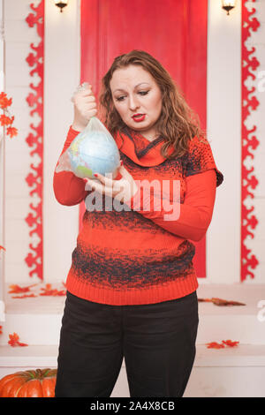 an emotional adult woman holds a planet in a plastic bag in her hands and shows irresponsible excessive consumer plastic. Stock Photo