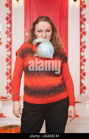 an emotional adult woman holds a planet in a plastic bag in her hands and shows irresponsible excessive consumer plastic. Stock Photo