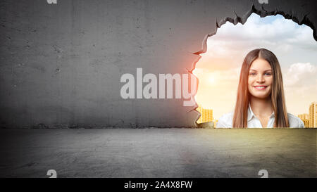 A giant woman's face looking from outside into a room through a large uneven opening in the wall. Stock Photo