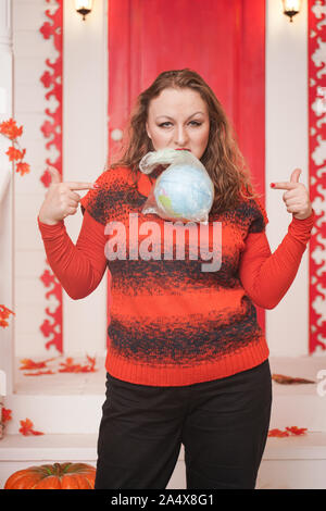 an emotional adult woman holds a planet in a plastic bag in her hands and shows irresponsible excessive consumer plastic. Stock Photo