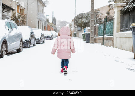 Young girl playing in street in snow in France back to camera Stock Photo