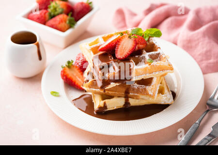 Belgian waffles with strawberry and chocolate sauce on white plate. Tasty breakfast, sweet dessert food Stock Photo