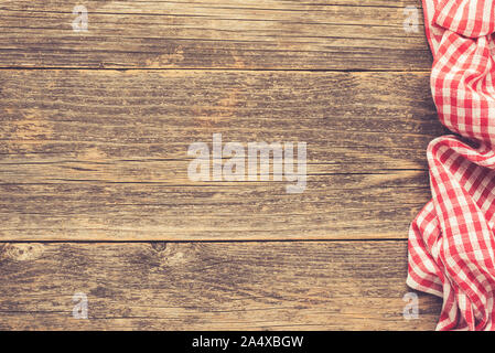 Wooden table with checkered textile. Food menu background, pizza or picnic concept. Rustic wooden planks and red plaid textile. Copy space Stock Photo