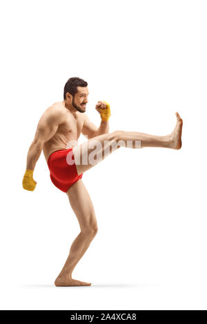 Full length profile shot of a fit man exercising kickboxing and pushing with his leg isolated on white background Stock Photo