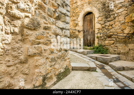 The wooden door of a house in Saint Guilhem le Desert is located in a stairway street Stock Photo