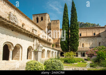 The cloister, its garden and the church of the abbey of Saint Guilhem le Desert Stock Photo