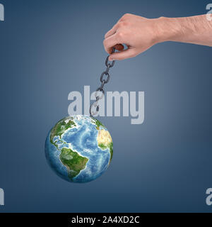 A large male hand holding a metal chain with a Earth globe handing on it and swinging. Stock Photo