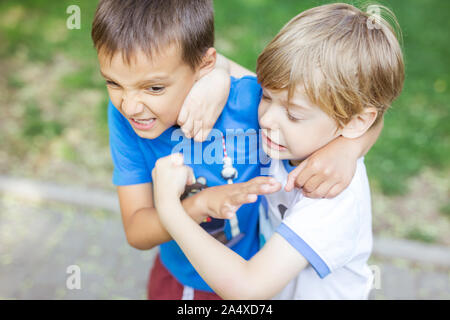 Two boys fighting outdoors. Friends wrestling in summer park. Siblings rivalry. Stock Photo