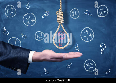 A businessman's hand with a hangman's noose above it with a red chalk question mark inside. Stock Photo