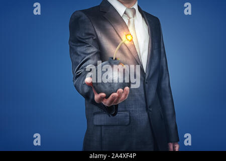 Businessman with bomb in hand on blue background Stock Photo