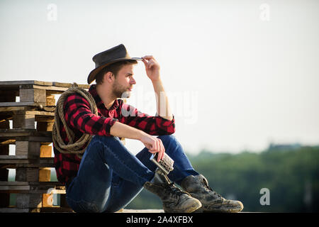 Let him ride a horse. wild west rodeo. Thoughtful man in hat drink whiskey. western cowboy. Vintage style man. Wild West retro cowboy. cowboy with lasso rope. Western. man checkered shirt on ranch. Stock Photo