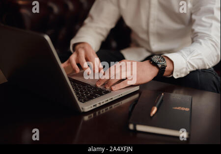 Businessman at work. Close-up top view of man working on laptop while sitting at the wooden desk startup Stock Photo