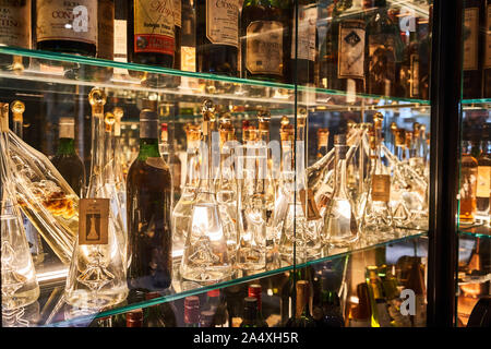 Glass decanters and old bottles in illuminated display cases at Víctor Montes restaurant, Bilbao, Spain Stock Photo