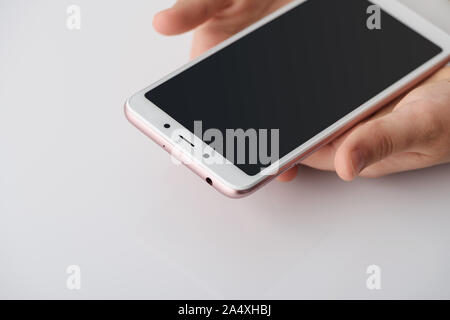 Smartphone in the hands of the girl. A girl is gently holding the smartphone with two hands. Stock Photo