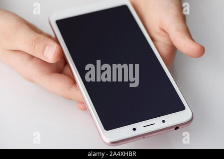Smartphone in the hands of the girl. A girl is gently holding the smartphone with two hands. Stock Photo