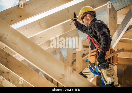 Construction Worker on Duty. Caucasian Contractor and the Wooden House Frame. Industrial Theme. Stock Photo