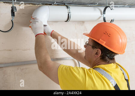 The worker is installing a ventilation system in the apartment. Stock Photo