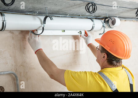 The worker is installing a ventilation system in the apartment. Stock Photo