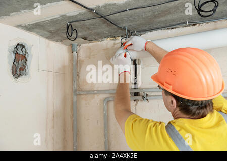 The worker is installing a ventilation system in the apartment. Stock Photo