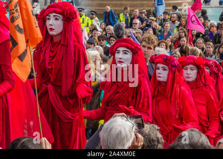 London, UK. 16th October 2019. The XR 'Red Brigade' walk through the crowd. An emergency protest in Trafalgar Square defends civil liberties and the right to protest after London Police ruled that even two people standing anywhere in London advocating action on climate change is an illegal assembly, and Monday's Queen's speech lacked any response to the Climate & Ecological Emergency. After the protest some sat down in Whitehall and were arrested, including George Monbiot.Peter Marshall/Alamy Live News Stock Photo