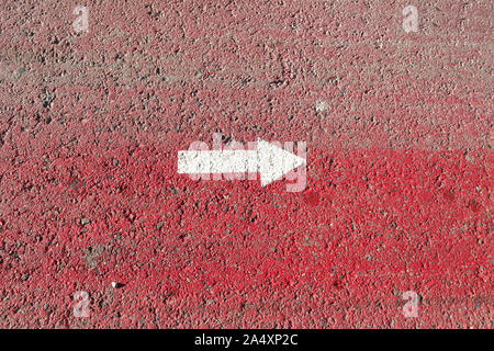 A white arrow indicates to the right on a red painted asphalt surface Stock Photo