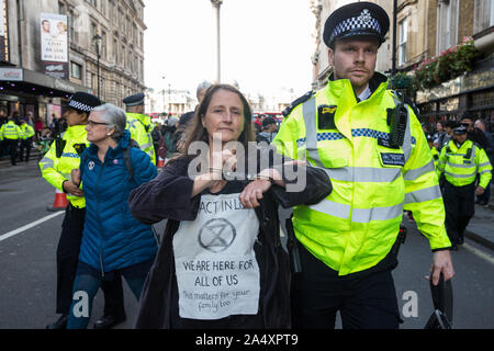 London, UK. 16 October, 2019. Police officers arrest a climate activist from Extinction Rebellion who had defied the Metropolitan Police prohibition on Extinction Rebellion Autumn Uprising protests throughout London under Section 14 of the Public Order Act 1986 by sitting in the road in Whitehall. Credit: Mark Kerrison/Alamy Live News