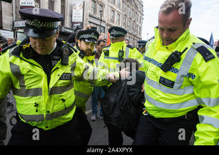 London, UK. 16 October, 2019. Police officers arrest a climate activist from Extinction Rebellion who had defied the Metropolitan Police prohibition on Extinction Rebellion Autumn Uprising protests throughout London under Section 14 of the Public Order Act 1986 by sitting in the road in Whitehall. Credit: Mark Kerrison/Alamy Live News