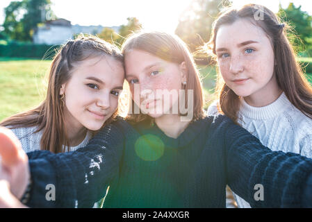 Three girls schoolgirls girlfriends, close-up, taking pictures themselves camera phone. Video recording, video call, online application Internet. In Stock Photo