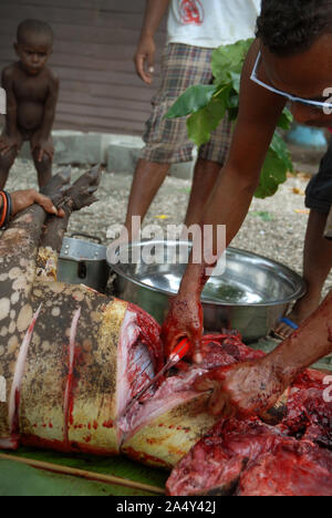 Men cutting up a newly slaughtered pig, Honiara, Solomon Islands. Stock Photo