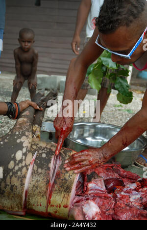 Men cutting up a newly slaughtered pig, Honiara, Solomon Islands. Stock Photo