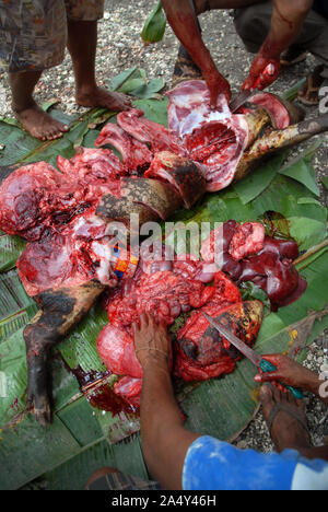 Men cutting up a newly slaughtered pig, Honiara, Solomon Islands. Stock Photo