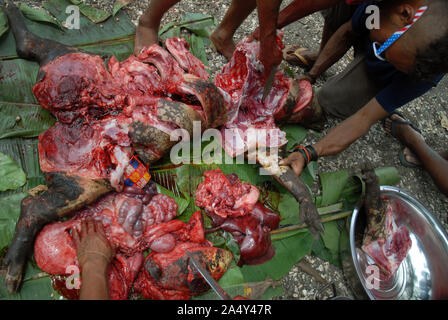 Men cutting up a newly slaughtered pig, Honiara, Solomon Islands. Stock Photo