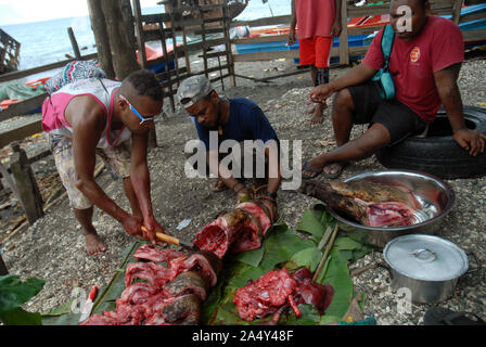 Men cutting up a newly slaughtered pig, Honiara, Solomon Islands. Stock Photo