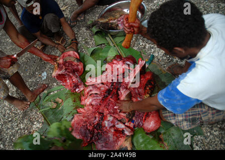 Men cutting up a newly slaughtered pig, Honiara, Solomon Islands. Stock Photo