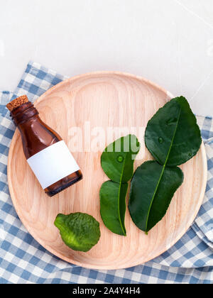 Alternative health care fresh  kaffir llime leaves and oils on marble background. Stock Photo