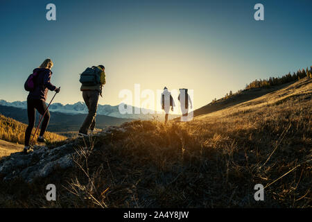 Group of young hikers walks in mountains at sunset time Stock Photo