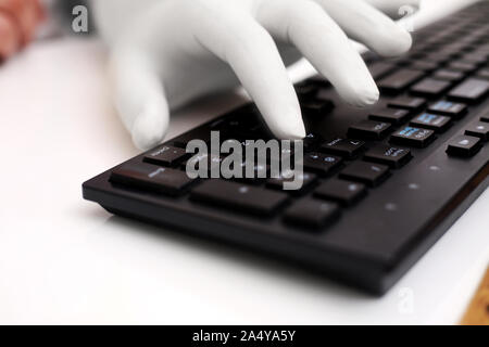 Picture of man typing with keyboard and wearing hand gloves. Isolated on white background. Stock Photo