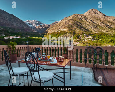 Traditional moroccan breakfast setting with mountain view in the background in Imlil, Morocco, High Atlas, table and chairs Stock Photo