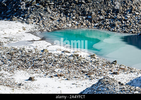 Türkisfarbener See auf der Macun Seenplatte im ersten Schnee im Herbst Stock Photo