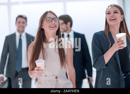 employees with cups of coffee discussing something during a work break Stock Photo