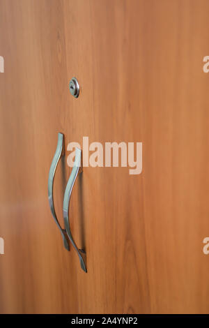 Beautiful doors of cupboard with keyhole and door handle from brass close-up. Background image of wooden doors of locker. Stock Photo