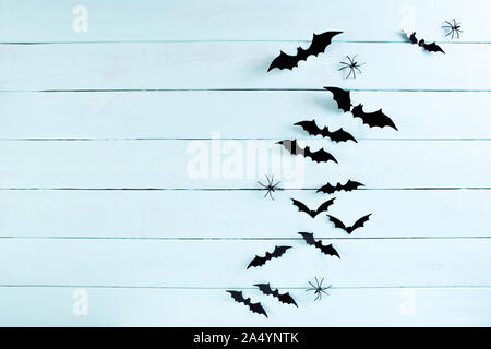 Top view of Halloween crafts, black paper bats flying over blue pastel wooden background with copy space for text. halloween concept. Stock Photo