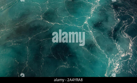 Close-up view of turquoise blue sea or ocean waves creating a marble effect with white flowing lines and blue marine, navy tones Stock Photo