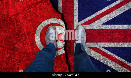 Business man stands on cracked flag of UK and Tunisia. Political concept Stock Photo