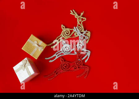 Three shiny Christmas deers carry 2 gift boxes with gifts and bows. Stock Photo