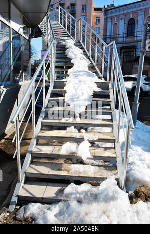 Gray stairs covered with white snow,  city landscape on background Stock Photo