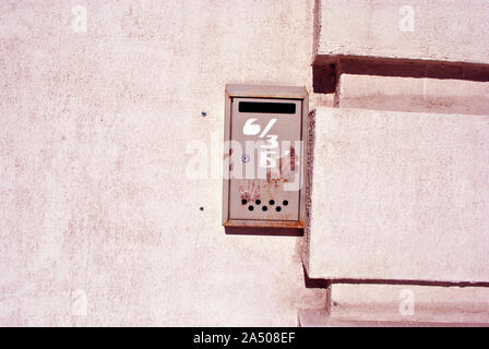 Red metal mailbox with white number painted on it, textured wall  grunge horizontal shabby background Stock Photo